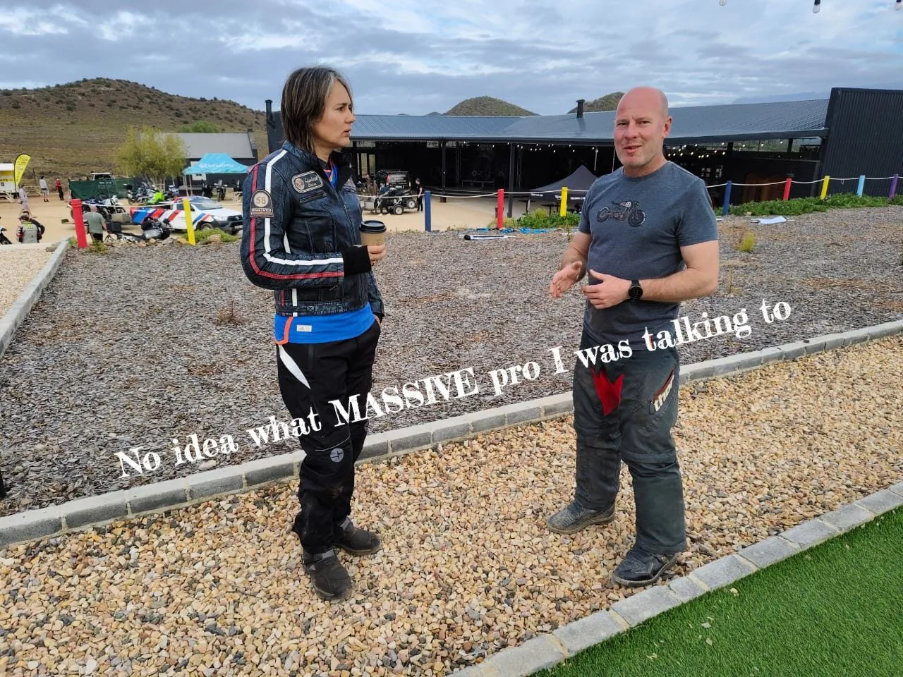 Two people standing on gravel at a roadside stop, captioned No idea what MASSIVE pro I was talking to.