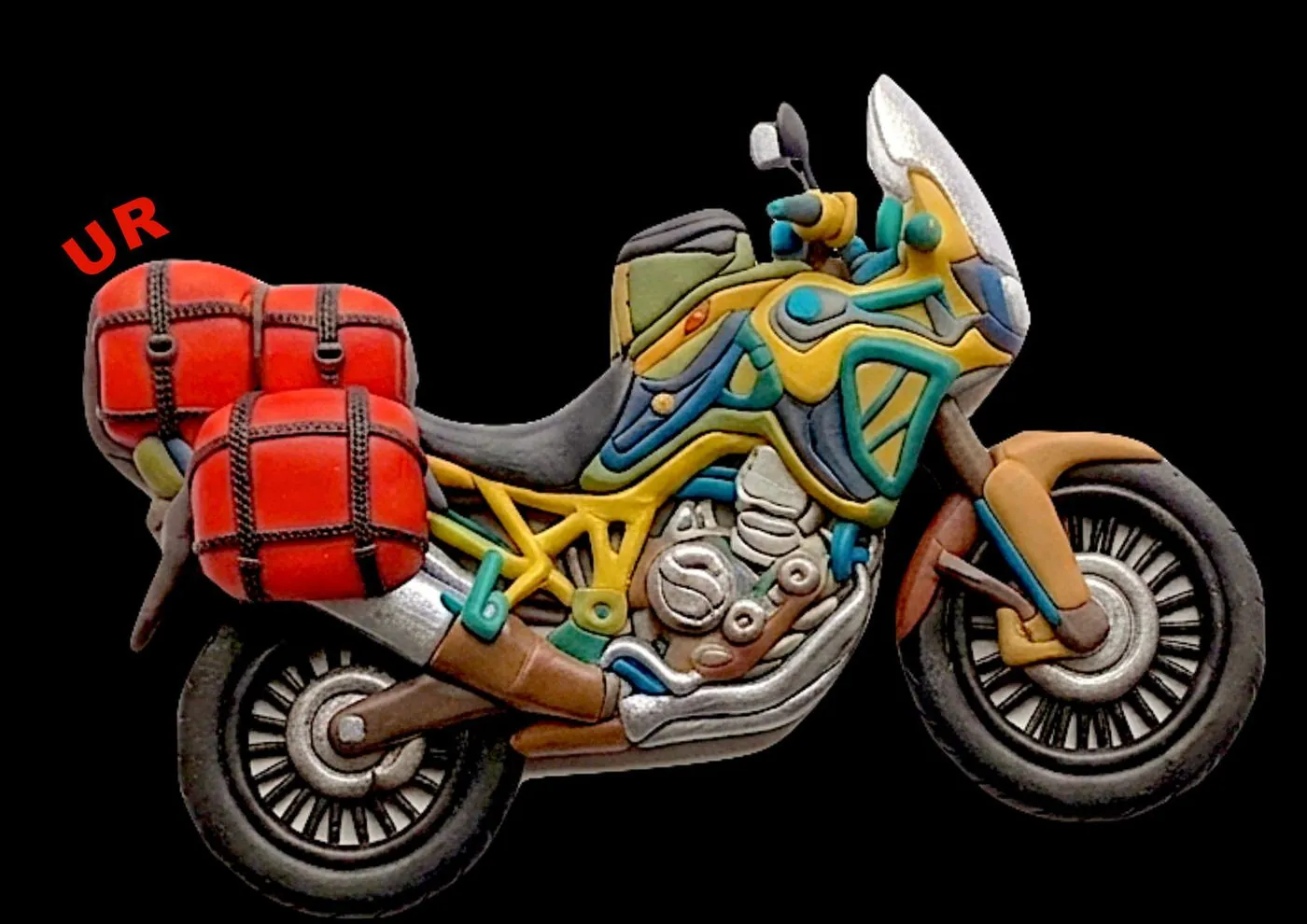A clay model of a yellow and blue adventure motorbike with red panniers on a black background, with the letters UR on it.