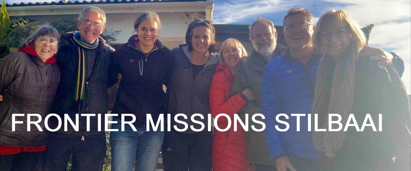 A group of women and men standing together, captioned Frontier Missions Stilbaai.