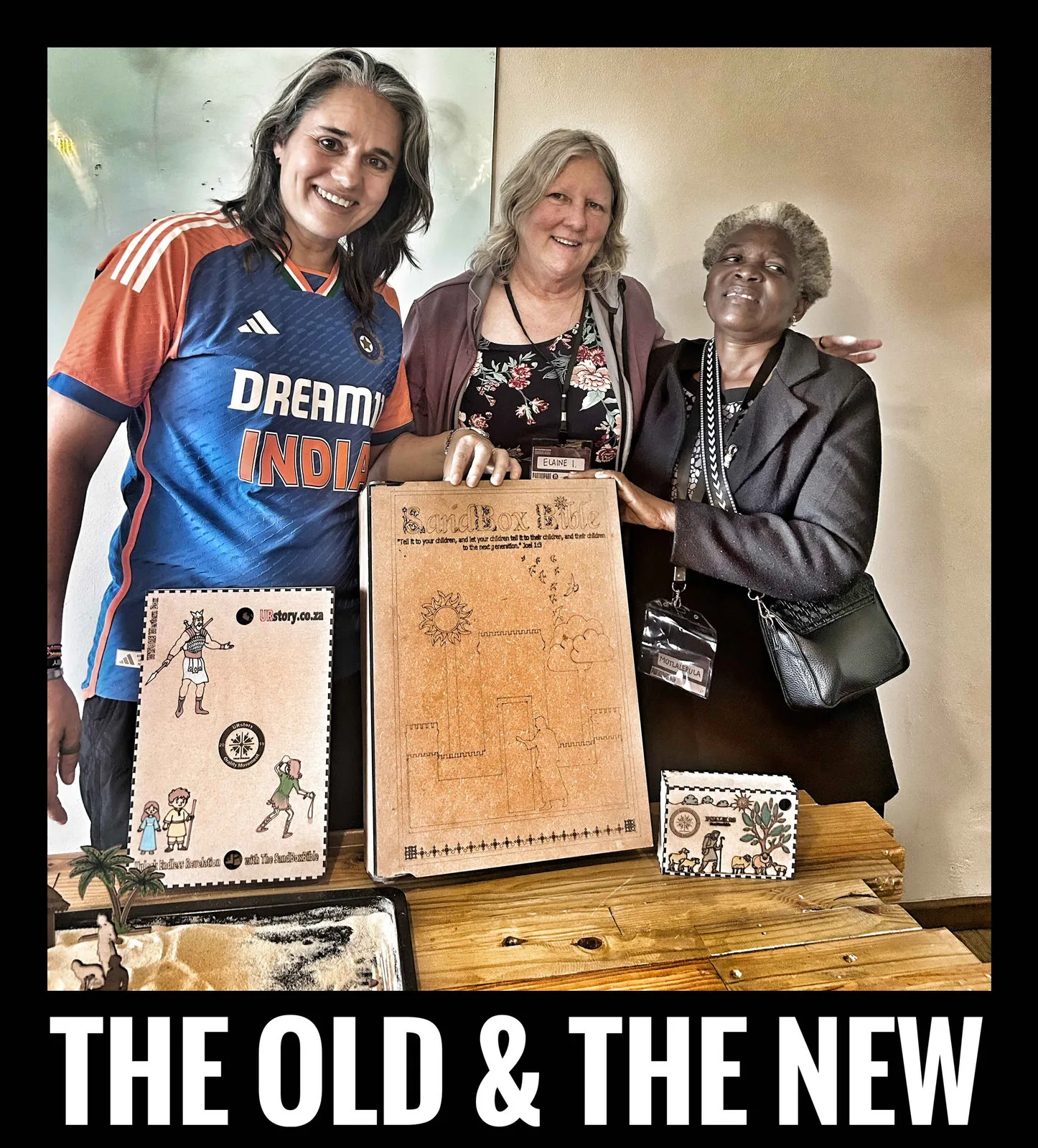 Three women smiling behind wooden SandBoxBible boxes, captioned The old and the new.