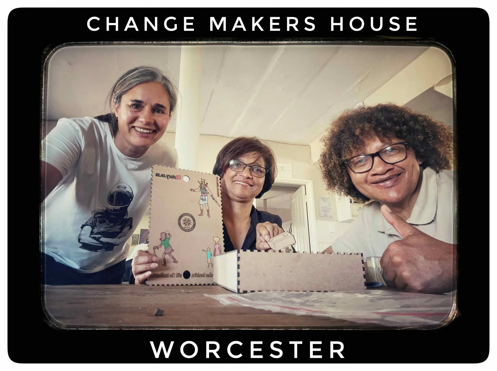 Three smiling women taking a selfie around a wooden box, captioned Change Makers House Worcester.