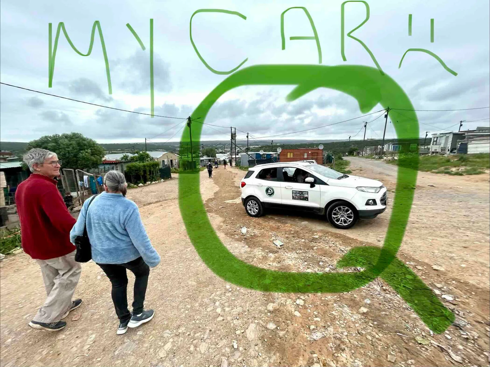A white car on a dirt road in the distance with two people walking in the foreground, and MY CAR with a sad face drawn in green over the photo.