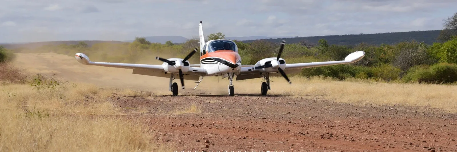 A small twin-engine plane on a dry dirt airstrip.